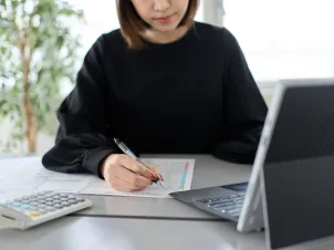 書類に電卓で計算する女性のイメージ